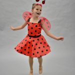a child dressed a a lady bug jumping. 