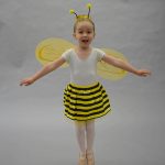 a child dressed as a bumble bee jumping