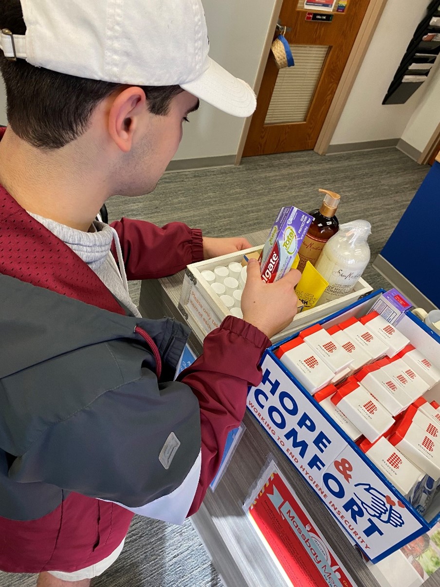 A MassBay Community College student picks up some toothpaste, soap, and other hygiene products at the MassBay Wellesley Hills campus, Wellesley Hills, MA, December 2023 (Photo/MassBay Community College).